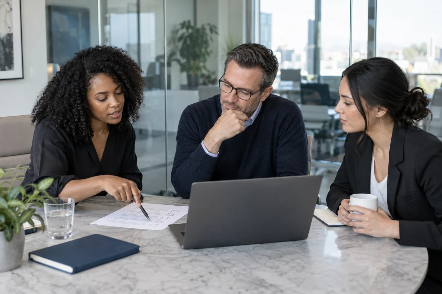 Three colleagues reviewing a requirements checklist together at a laptop