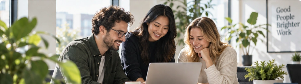 Three colleagues discussing work together at a laptop in a bright studio